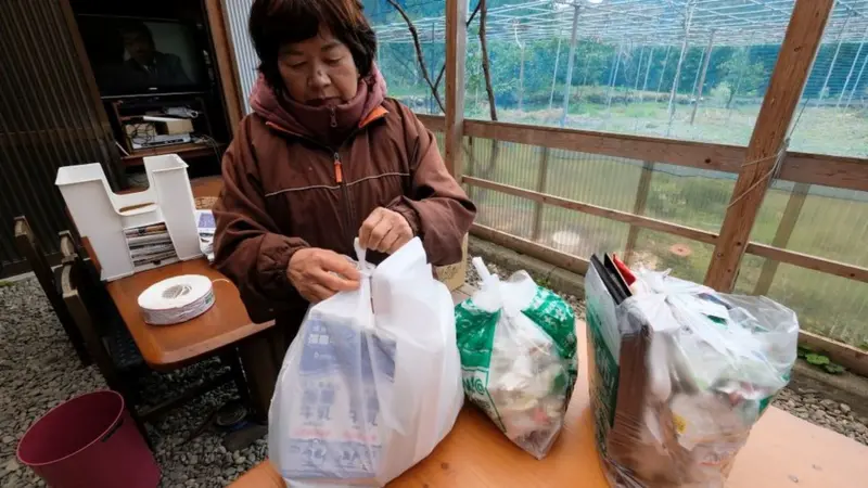 Mujer japonesa separando residuos domésticos, ejemplo de cultura de reciclaje inspirada en la filosofía Mottainai.