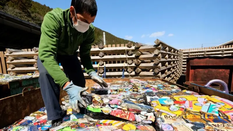 Hombre en Japón reciclando plásticos comprimidos, ejemplo de la filosofía de residuo cero y del Mottainai moderno.